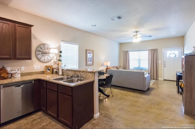 a kitchen with a stove a sink a counter space and living room