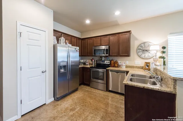 a kitchen with granite countertop a refrigerator stove and sink
