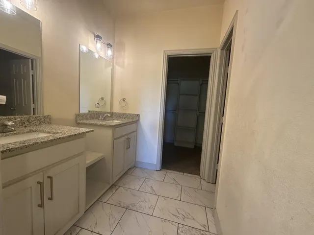 a spacious bathroom with a granite countertop sink and a mirror