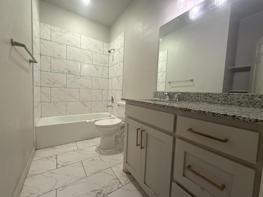 129 Towering Oaks Tool, TX 75143 - Photo 13 of 20 a bathroom with a granite countertop sink a toilet and bathtub