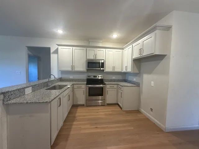a kitchen with granite countertop a sink stainless steel appliances and cabinets