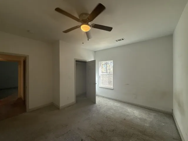 an empty room with a window and a fan