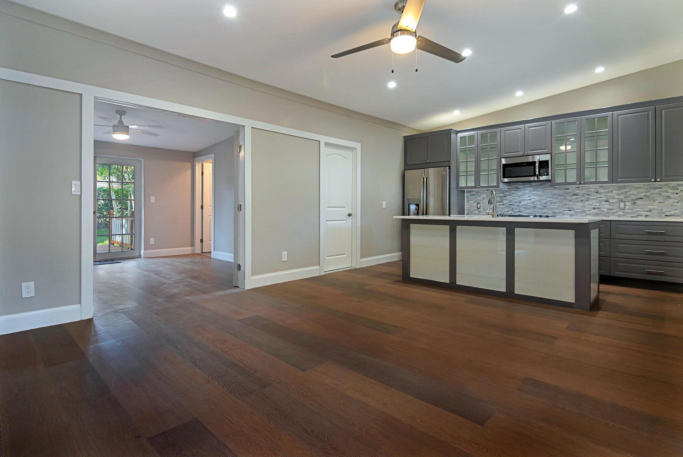 959 Southwest 18th Street, Unit W Boca Raton, FL 33486 - Photo 2 of 18 an empty room with wooden floor and kitchen view