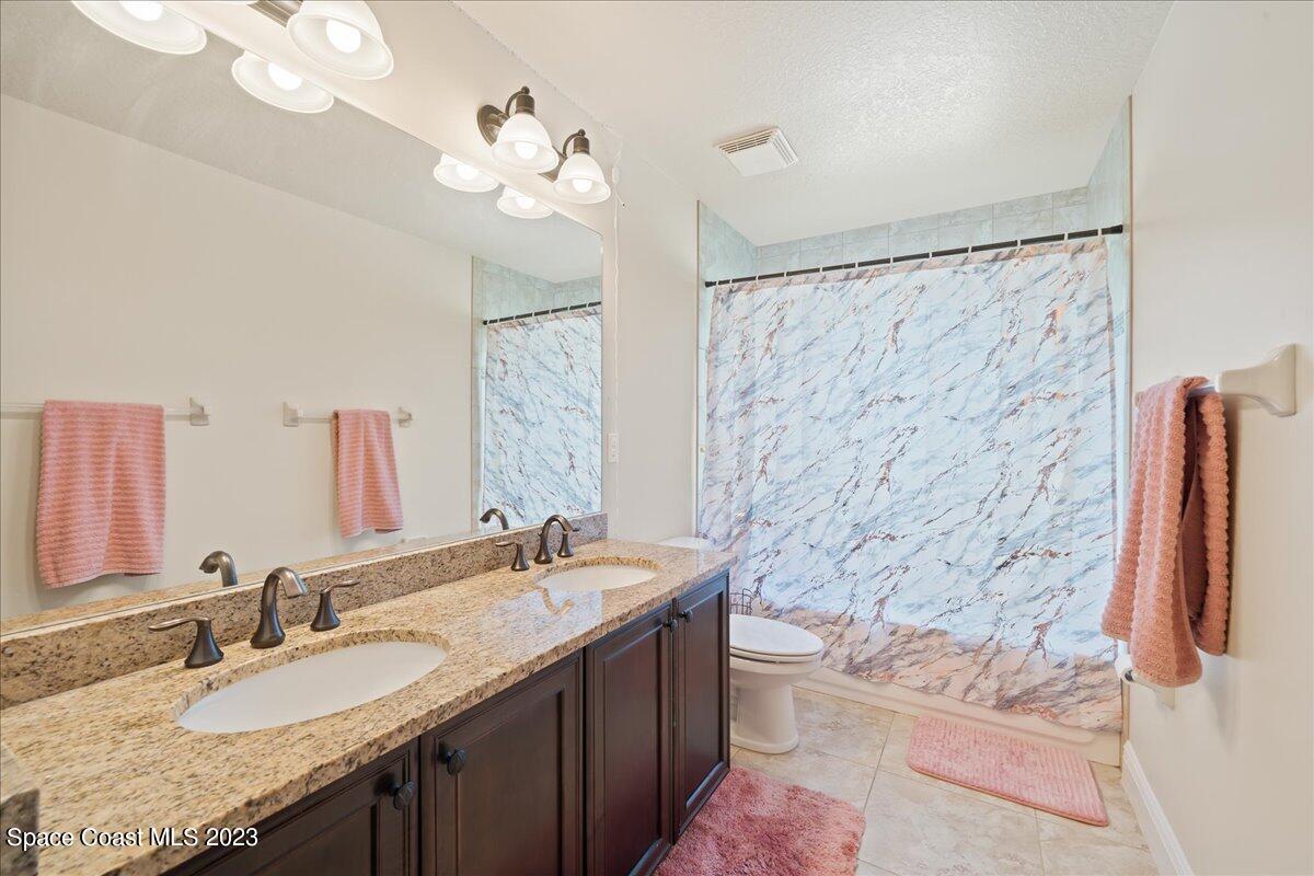 671 Palm Drive Satellite Beach, FL 32937 - Photo 32 of 69 a bathroom with a granite countertop sink a toilet and a mirror