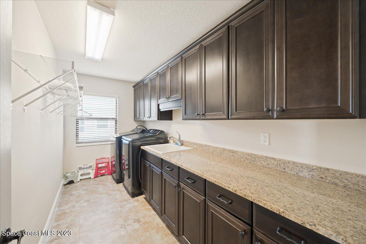 671 Palm Drive Satellite Beach, FL 32937 - Photo 35 of 69 a kitchen with granite countertop a sink stainless steel appliances wooden floor and cabinets