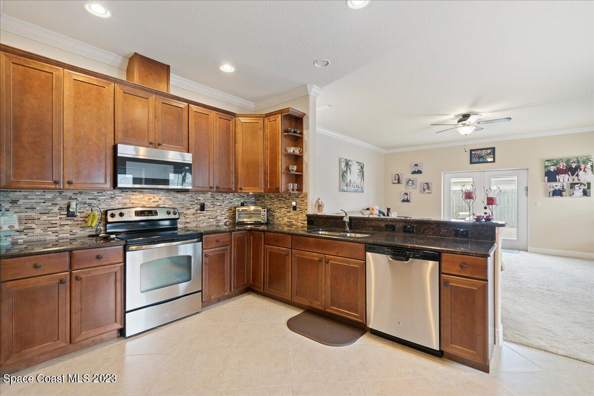 671 Palm Drive Satellite Beach, FL 32937 - Photo 47 of 69 a kitchen with stainless steel appliances granite countertop a stove top oven a sink dishwasher and a microwave oven on the blue kitchen countertops
