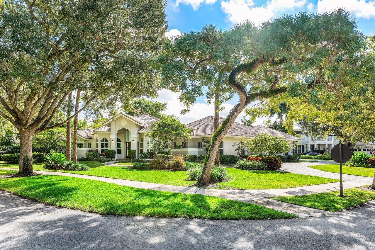 2450 Northwest 41st Street Boca Raton, FL 33431 - Photo 5 of 62 a view of a white house in front of a big yard with plants and large trees