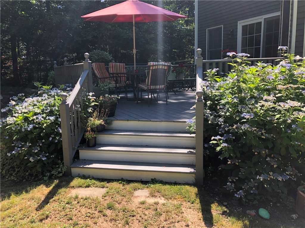 6 Princess Pine Road Lincoln, RI 02865 - Photo 34 of 40 Another perspective of the deck shows it's unique design and easy access to the back yard. Flowering perennials are a beautiful accent.