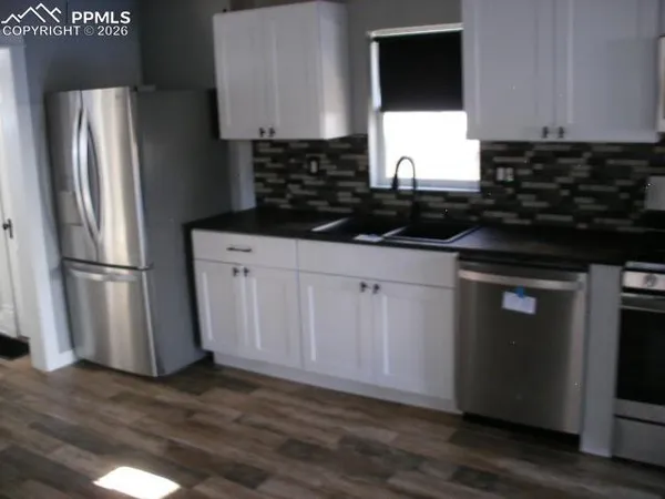 a kitchen with granite countertop a refrigerator sink and cabinets