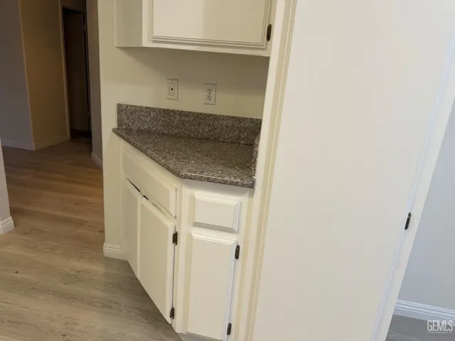 a hallway with granite countertop white cabinets and a wooden floor