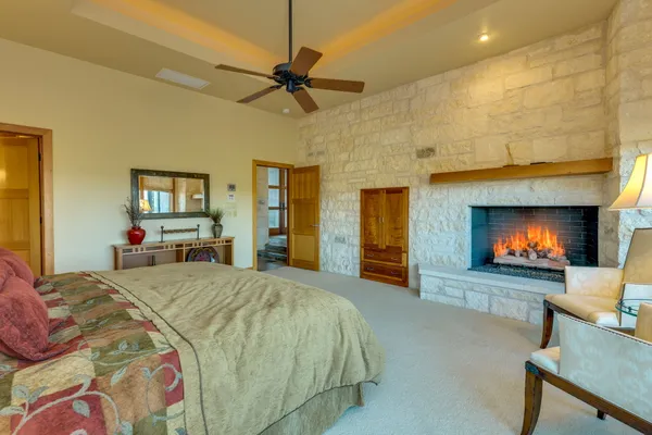 a spacious bedroom with a bed a flat screen tv and a fireplace