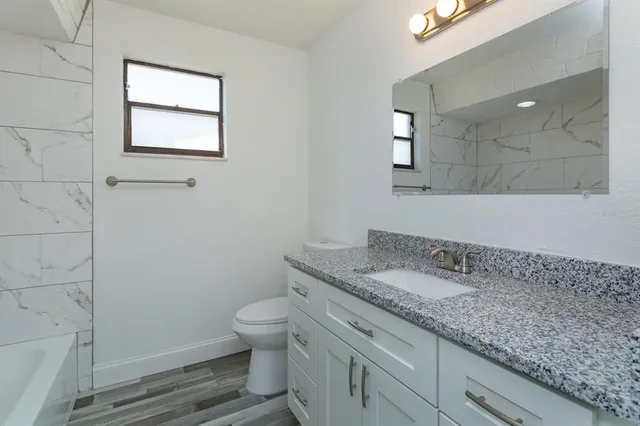 a bathroom with a granite countertop toilet sink and mirror