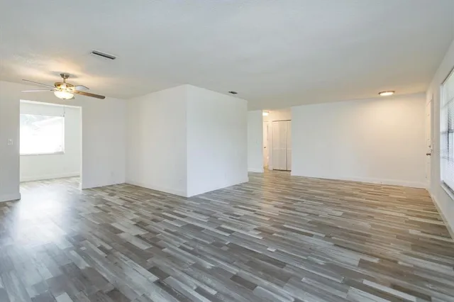a view of empty room with wooden floor and fan