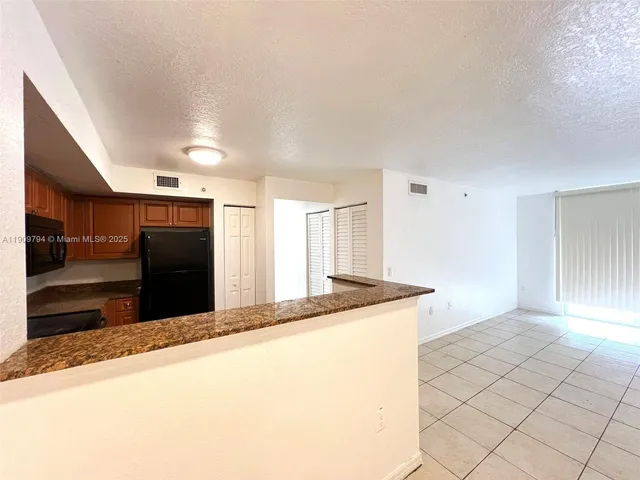 a view of kitchen with granite countertop cabinets and refrigerator