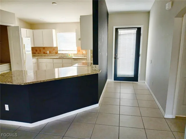 a kitchen with granite countertop a refrigerator and a stove top oven