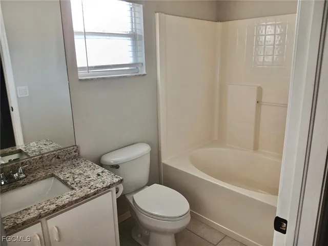 a bathroom with a granite countertop toilet a sink and a bathtub