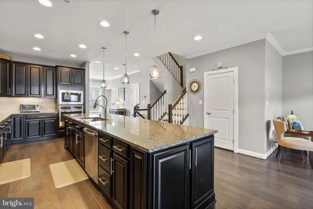 a kitchen with stainless steel appliances granite countertop a sink a stove and a wooden floors