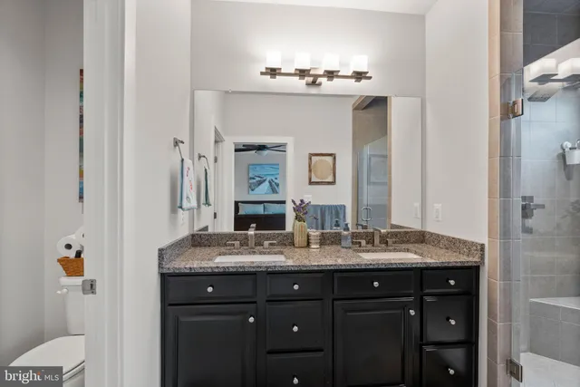 a bathroom with a granite countertop sink a mirror and shower view