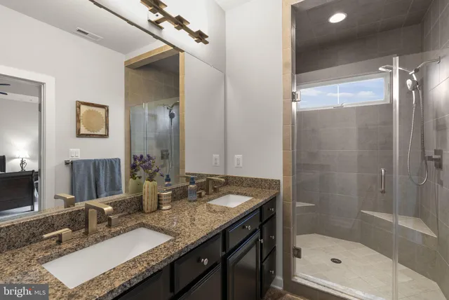 a bathroom with a granite countertop sink a mirror and a shower