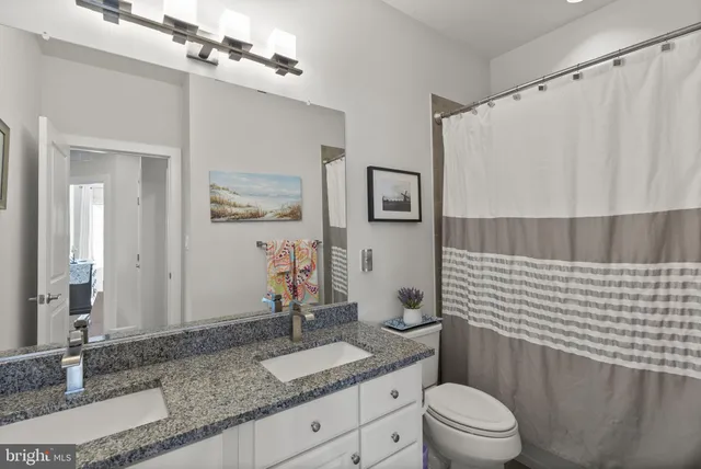 a bathroom with a granite countertop sink mirror vanity and toilet