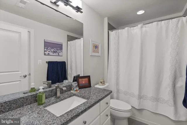 a bathroom with a granite countertop sink mirror vanity and toilet