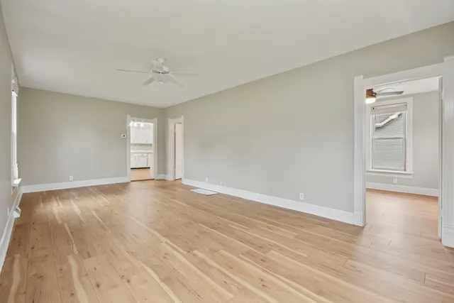 a view of empty room with wooden floor and ceiling fan