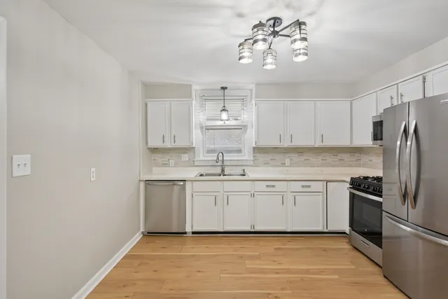 a kitchen with a sink dishwasher a refrigerator and white cabinets