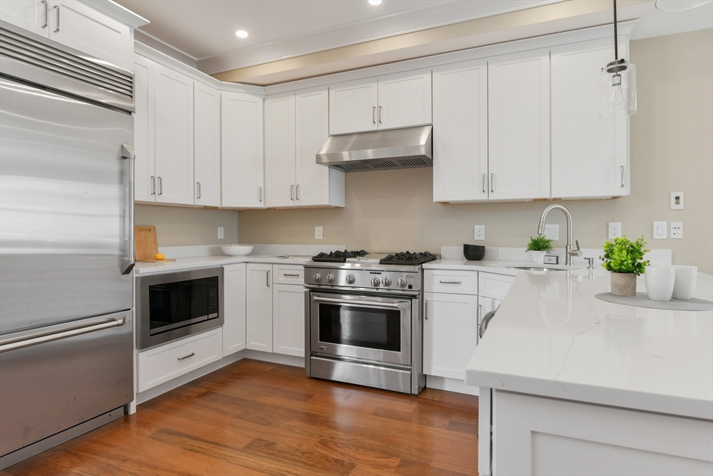 111 Bolton Street, Unit 2 Boston, MA 02127 - Photo 3 of 36 a kitchen with cabinets stainless steel appliances and wooden floor