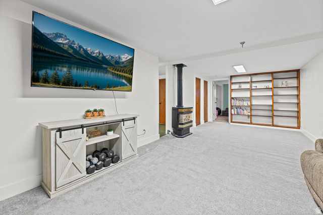 822 Pinewood Circle Price, UT 84501 - Photo 19 of 49 Spacious room featuring light gray carpeting, built-in shelving, a freestanding wood-burning stove, and a recessed ceiling light