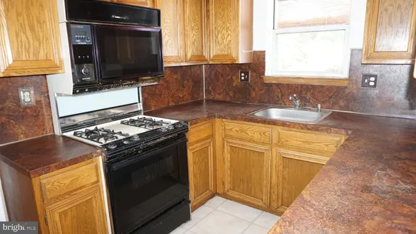 a kitchen with granite countertop a stove top oven cabinetry a sink and a window