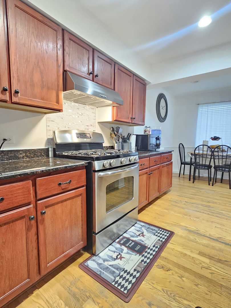 441 Commanche Trail Wheeling, IL 60090 - Photo 5 of 26 a kitchen with stainless steel appliances granite countertop a stove a sink dishwasher and cabinets with wooden floor