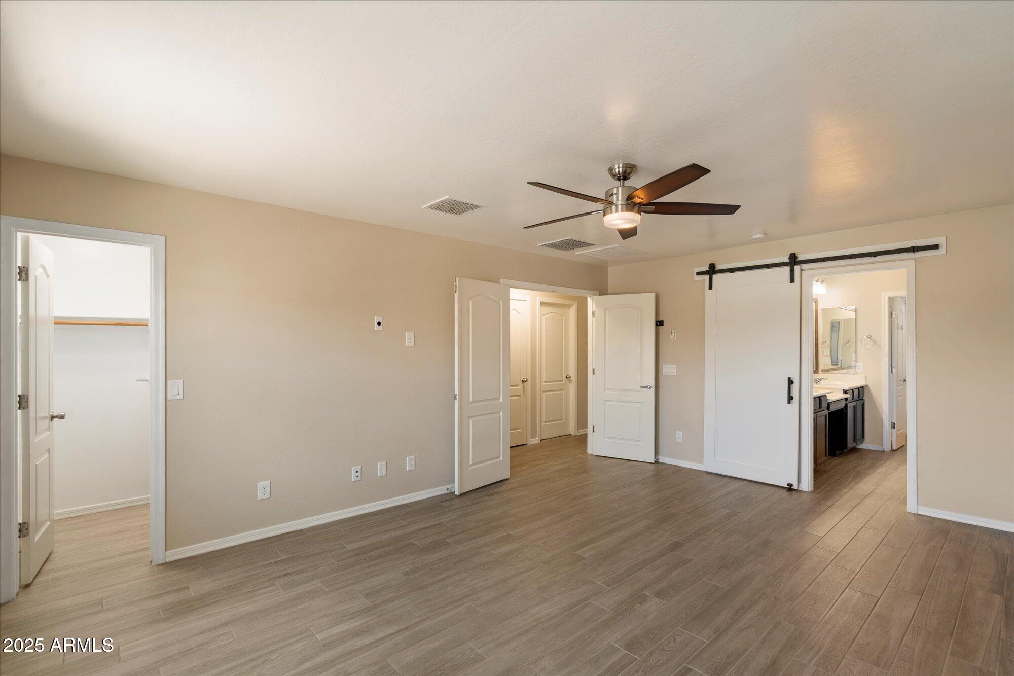 737 East Harwell Road Phoenix, AZ 85042 - Photo 16 of 28 an empty room to hallway with wooden floor and a ceiling fan