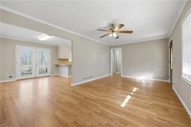 a view of an empty room with a window and wooden floor