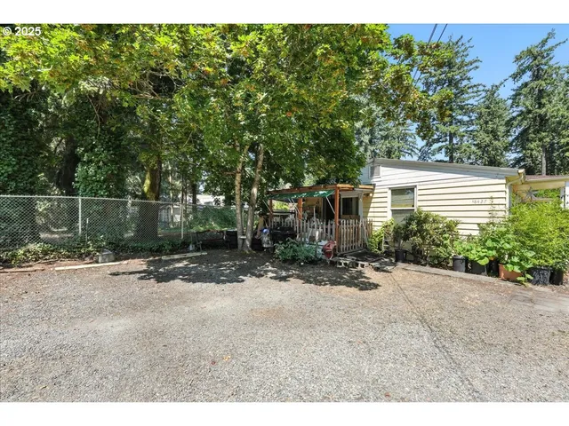 a backyard of a house with plants and trees with wooden fence