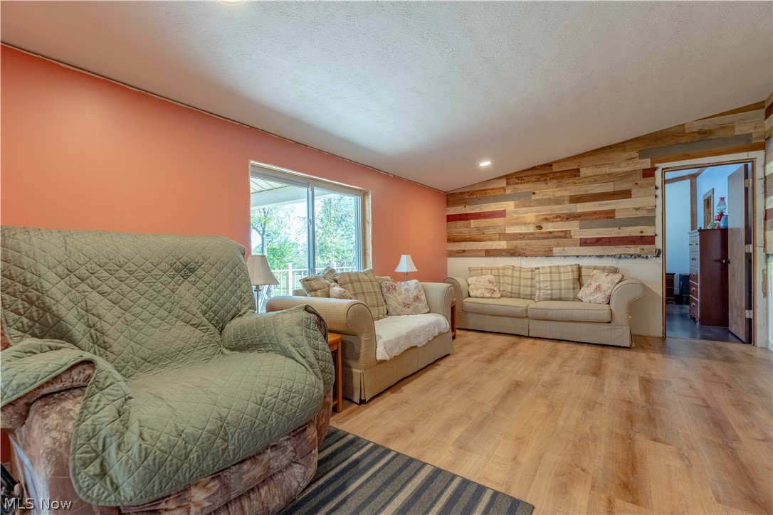 5267 Apollo Road Northeast Salineville, OH 43945 - Photo 5 of 33 Living room with vaulted ceiling, wood walls, wood finished floors, and a textured ceiling