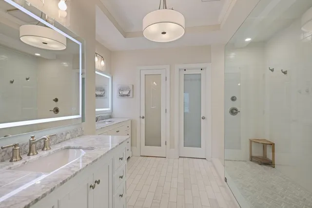 a spacious bathroom with a granite countertop sink a mirror and a shower