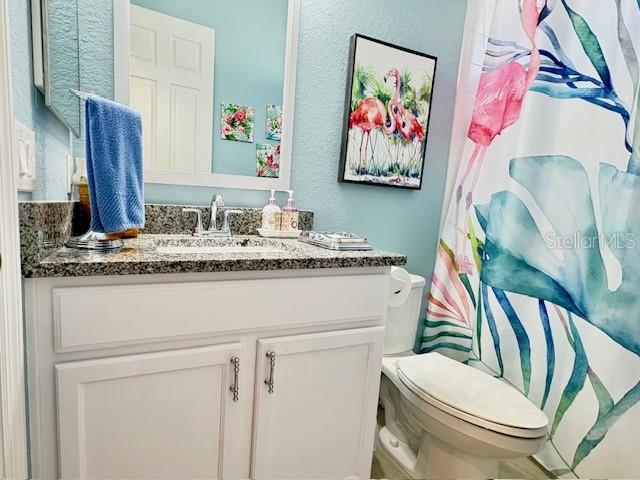 6261 Pinehurst Loop Winter Haven, FL 33884 - Photo 40 of 76 a bathroom with a granite countertop sink a toilet and a mirror