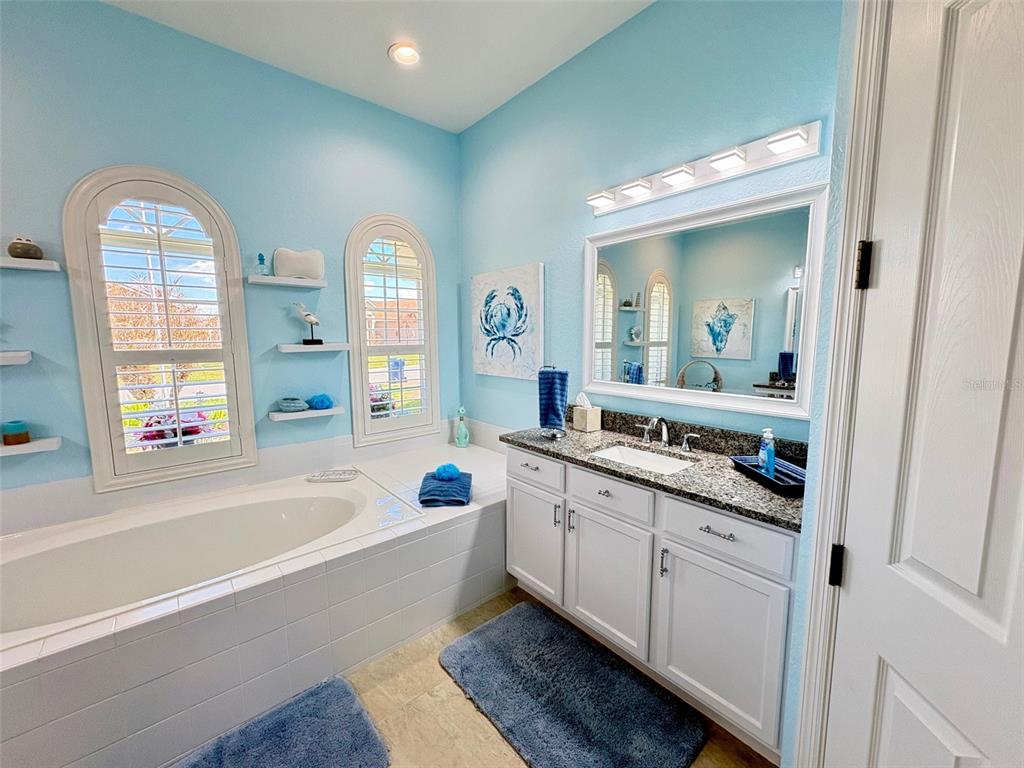 6261 Pinehurst Loop Winter Haven, FL 33884 - Photo 54 of 76 a bathroom with a tub a double vanity sink and a large mirror
