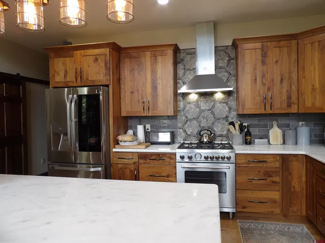 a kitchen with stainless steel appliances granite countertop a stove top oven a refrigerator and cabinets