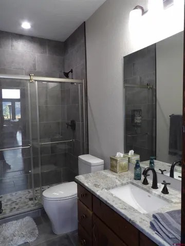 a bathroom with a granite countertop sink a toilet and shower