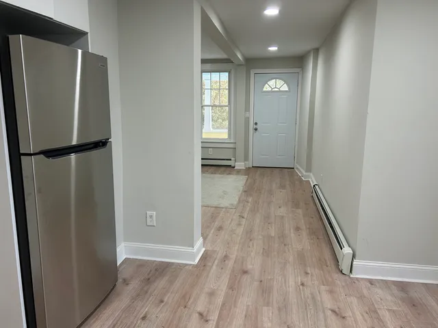 a view of a hallway with wooden floor and a refrigerator