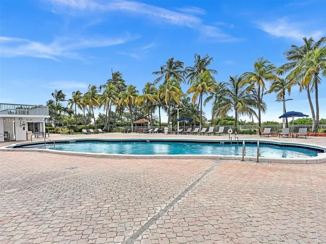 a view of swimming pool with outdoor seating and trees in the background