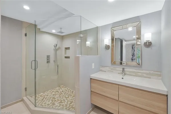 a bathroom with a sink a toilet a glass door shower and a mirror