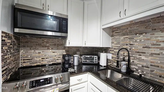 a kitchen with granite countertop a stove and a microwave