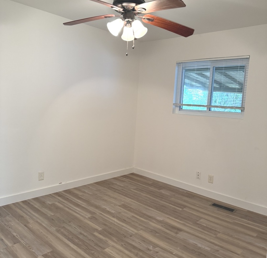 533 Redwood Road Bolingbrook, IL 60440 - Photo 12 of 18 an empty room with wooden floor fan and windows