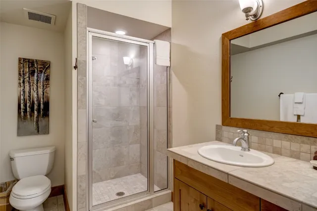 a bathroom with a granite countertop sink toilet and shower
