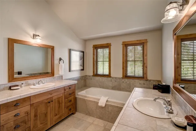 a bathroom with a tub double sink window and mirror