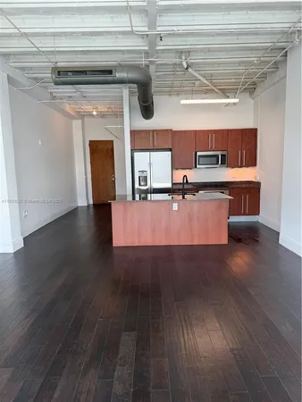 a living room with stainless steel appliances kitchen island granite countertop a wooden floor