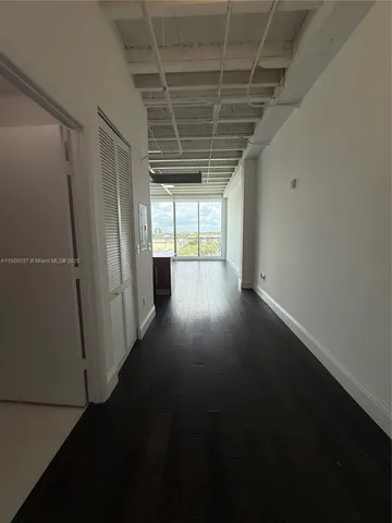 an empty room with wooden floor and windows with curtains