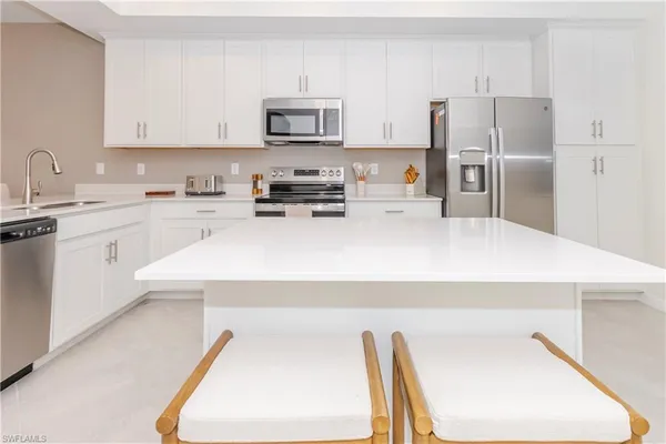 a kitchen with a sink a stove a refrigerator and white cabinets